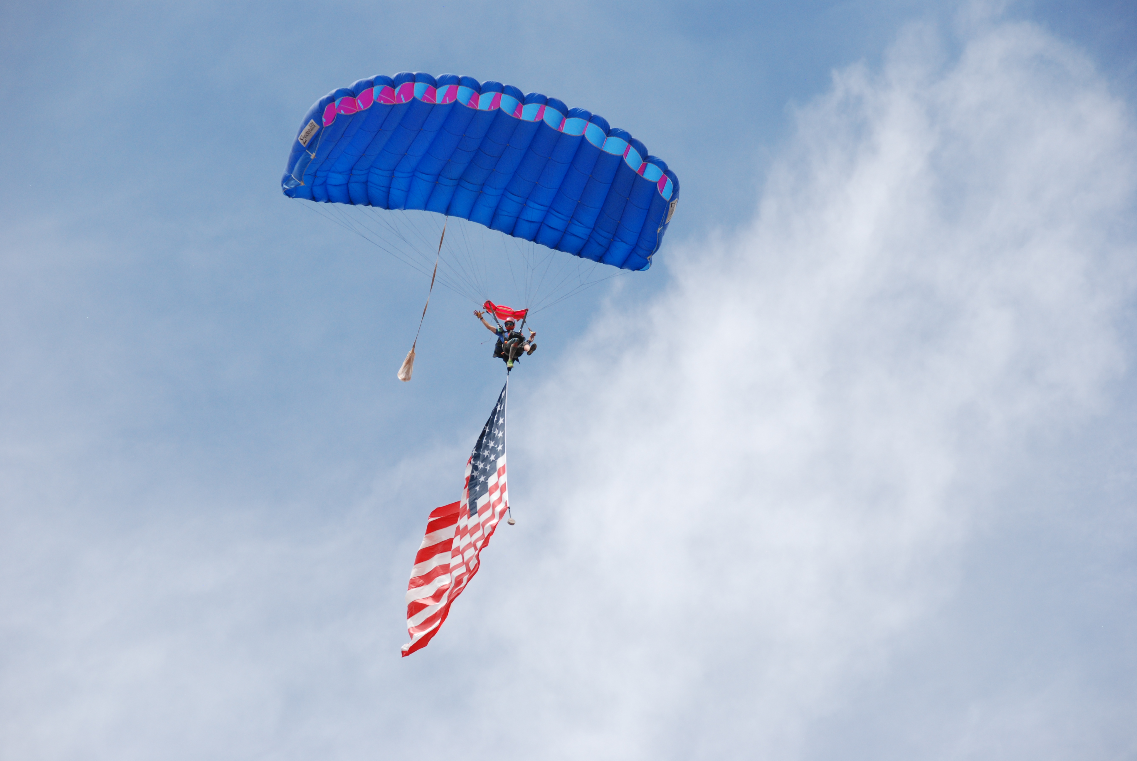 A skydiver carries the American flag over Sisters Eagle Airport during a community event